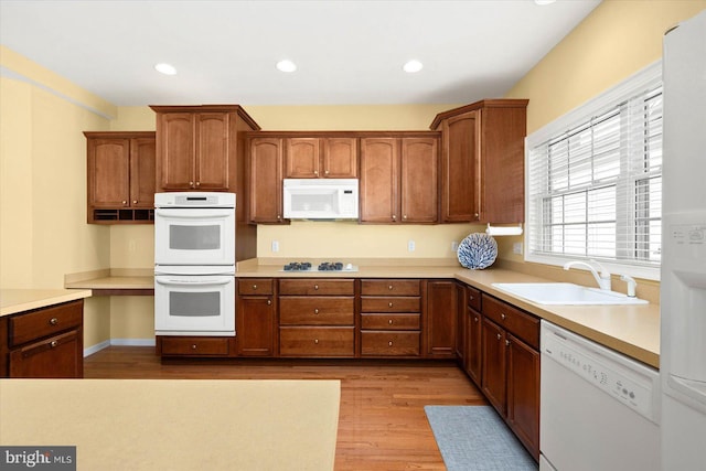 kitchen with white appliances, light wood-type flooring, and sink