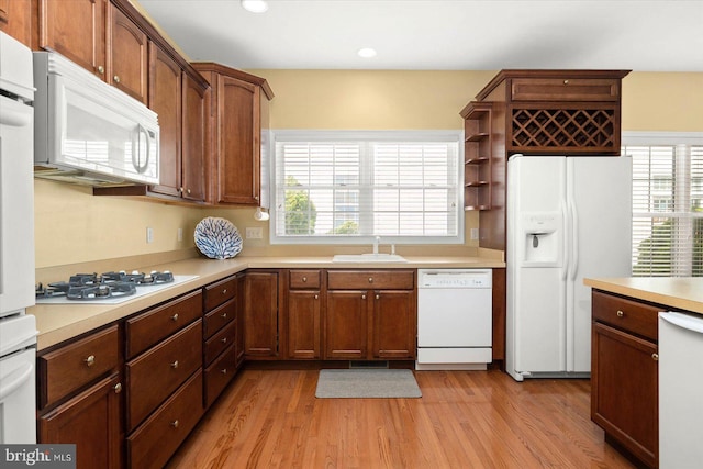 kitchen featuring sink, white appliances, and light wood-type flooring