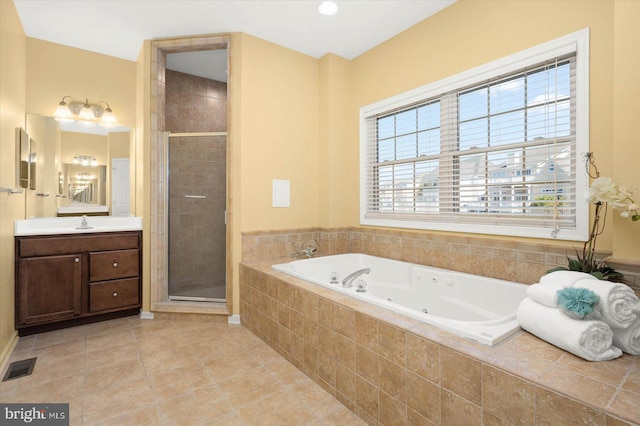 bathroom with separate shower and tub, vanity with extensive cabinet space, and tile flooring