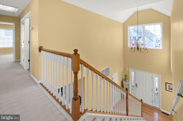 carpeted entryway featuring plenty of natural light, a notable chandelier, and lofted ceiling