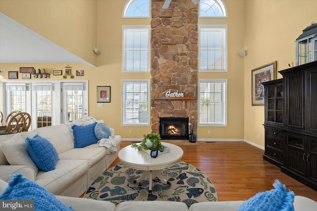 living room featuring dark hardwood / wood-style floors, a stone fireplace, and a high ceiling