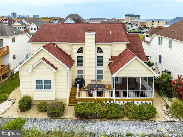 rear view of property with a wooden deck and a sunroom