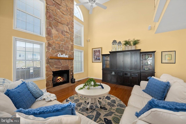 living room featuring ceiling fan, dark hardwood / wood-style floors, a fireplace, and a towering ceiling