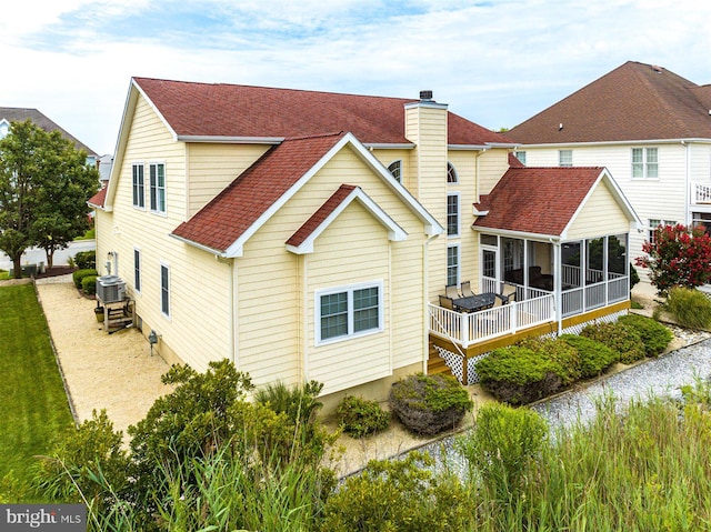 rear view of house with central AC unit and a sunroom