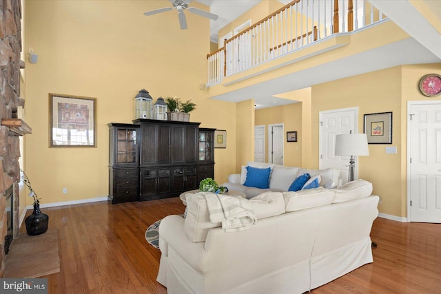 living room featuring ceiling fan, a towering ceiling, and dark wood-type flooring