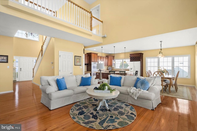 living room with light hardwood / wood-style floors and a towering ceiling