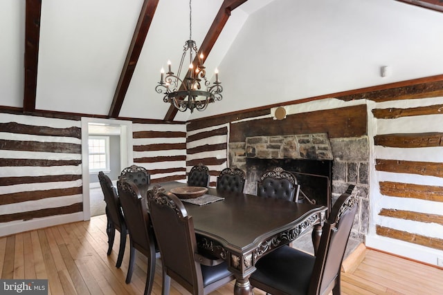 dining room with a chandelier, lofted ceiling with beams, a fireplace, and light wood-type flooring