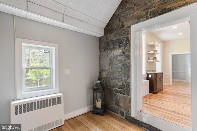 interior space featuring a drop ceiling, light hardwood / wood-style flooring, vanity, and radiator heating unit