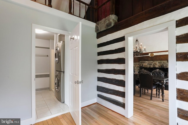 staircase with radiator, light tile flooring, stacked washing maching and dryer, and a chandelier