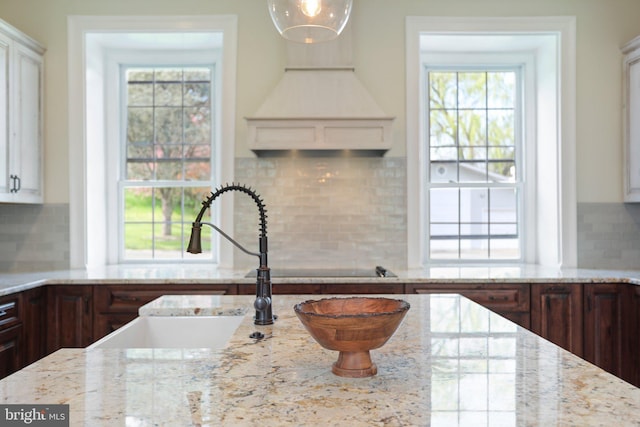 kitchen featuring backsplash, dark brown cabinetry, sink, and light stone countertops