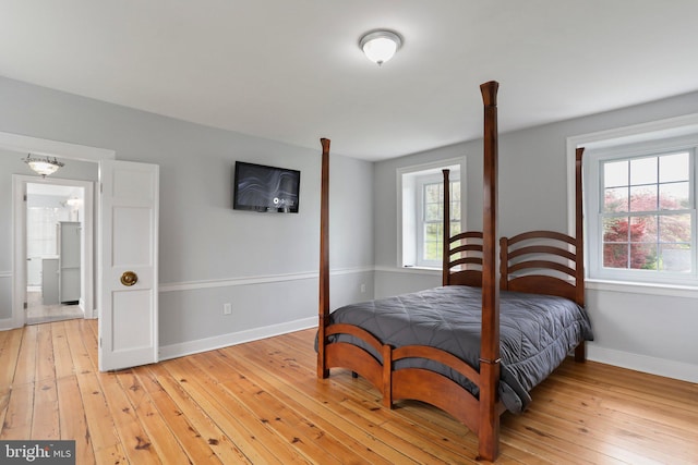 bedroom with ensuite bathroom and light wood-type flooring