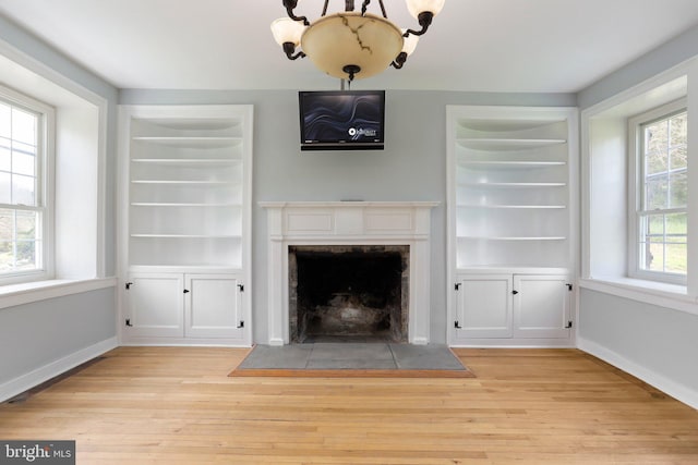 unfurnished living room with plenty of natural light, light hardwood / wood-style floors, and built in shelves