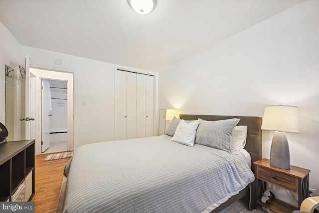 bedroom with a closet, ensuite bathroom, and hardwood / wood-style floors