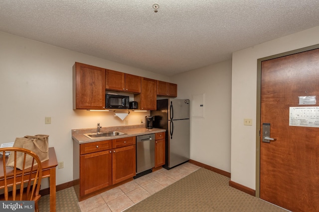 kitchen with a textured ceiling, light tile floors, appliances with stainless steel finishes, and sink