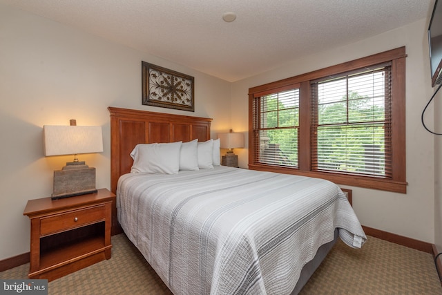 bedroom with a textured ceiling and dark carpet