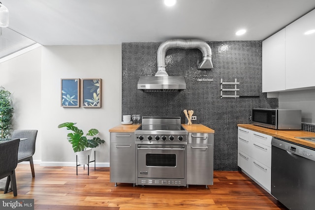 kitchen with appliances with stainless steel finishes, hardwood / wood-style flooring, and wooden counters