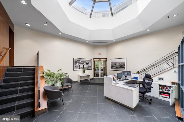 tiled home office with a skylight, a towering ceiling, and a tray ceiling