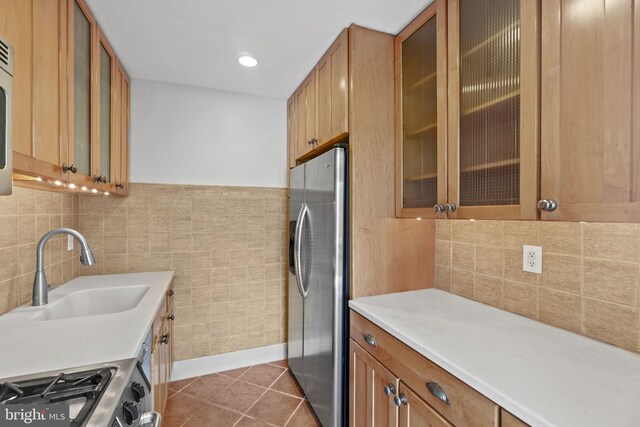 kitchen with tile walls, sink, stainless steel fridge with ice dispenser, dark tile flooring, and tasteful backsplash