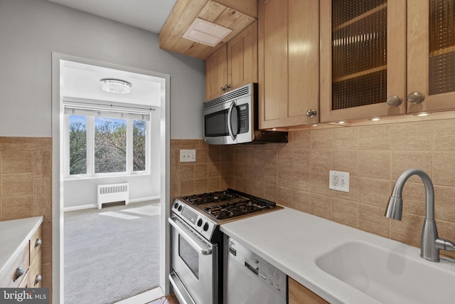 kitchen featuring light colored carpet, radiator heating unit, tasteful backsplash, white appliances, and sink