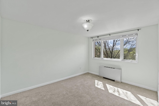 spare room featuring radiator heating unit and light colored carpet