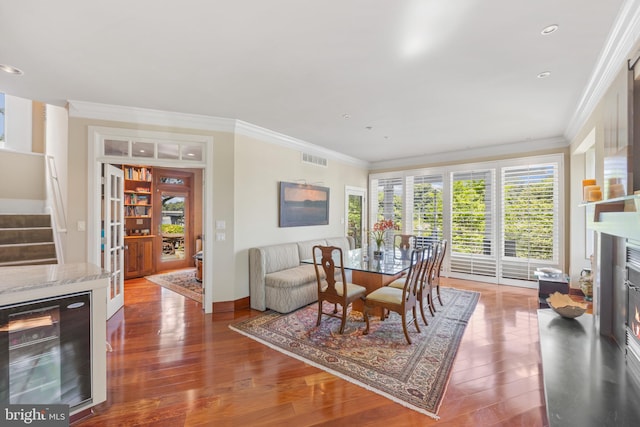 dining area featuring wood-type flooring, crown molding, and wine cooler