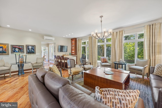 living room with an inviting chandelier, an AC wall unit, and light hardwood / wood-style flooring