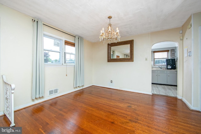 unfurnished room with dark hardwood / wood-style floors, an inviting chandelier, and plenty of natural light