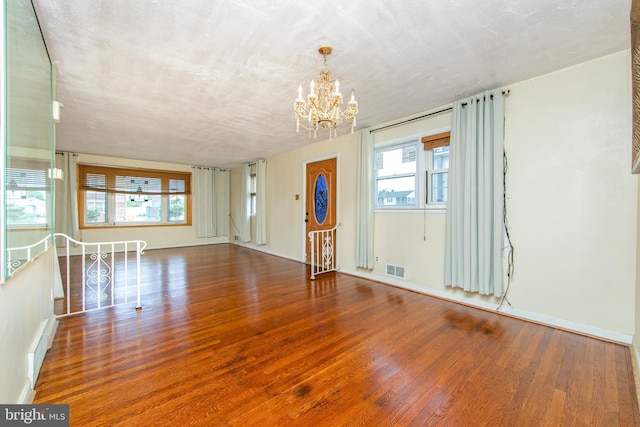 spare room featuring wood-type flooring, a textured ceiling, and a wealth of natural light