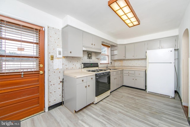 kitchen featuring gray cabinetry, white appliances, sink, and light hardwood / wood-style flooring