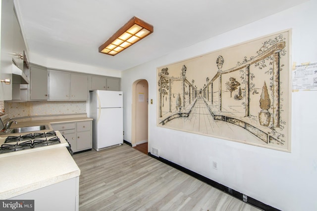 kitchen with stainless steel range, sink, light hardwood / wood-style flooring, white refrigerator, and gray cabinets