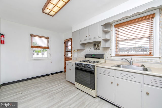 kitchen featuring light hardwood / wood-style floors, plenty of natural light, white gas range, and sink