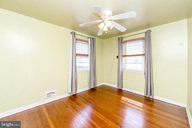 empty room featuring wood-type flooring, a wealth of natural light, and ceiling fan