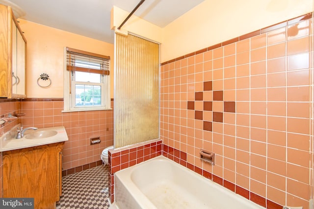 bathroom featuring tile patterned flooring, vanity, toilet, and tile walls