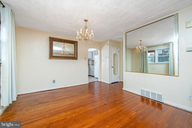 spare room featuring hardwood / wood-style floors and an inviting chandelier