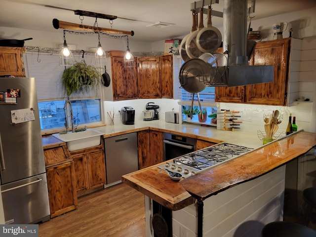 kitchen featuring sink, tasteful backsplash, light wood-type flooring, stainless steel appliances, and kitchen peninsula