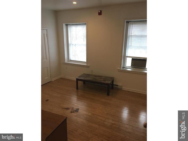 spare room featuring dark wood-type flooring and a baseboard heating unit