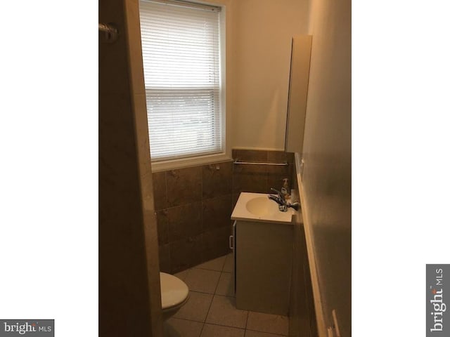 bathroom with toilet, large vanity, tile walls, and tile flooring