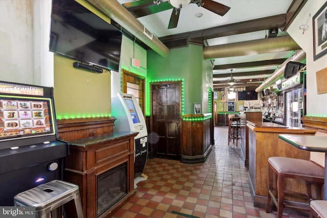 miscellaneous room with beam ceiling, bar, dark tile floors, and ceiling fan