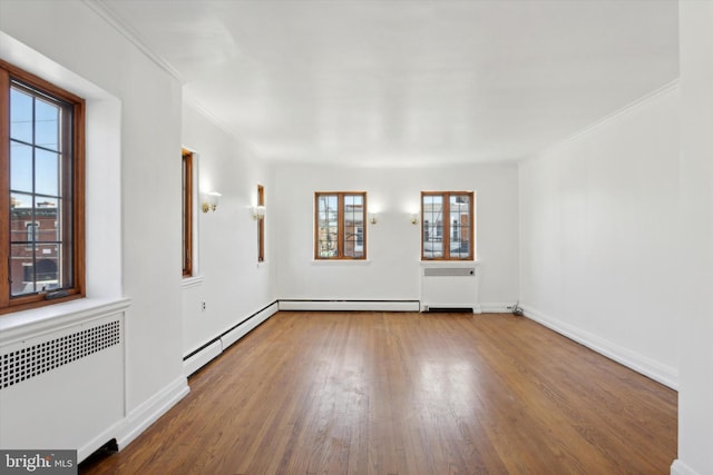 unfurnished room featuring radiator heating unit, plenty of natural light, and dark hardwood / wood-style floors