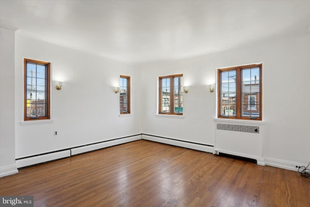 spare room with a baseboard heating unit, radiator, dark hardwood / wood-style floors, and crown molding