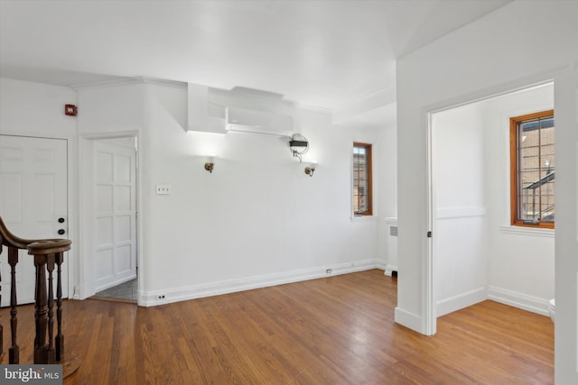 spare room with wood-type flooring, radiator heating unit, and a wall unit AC