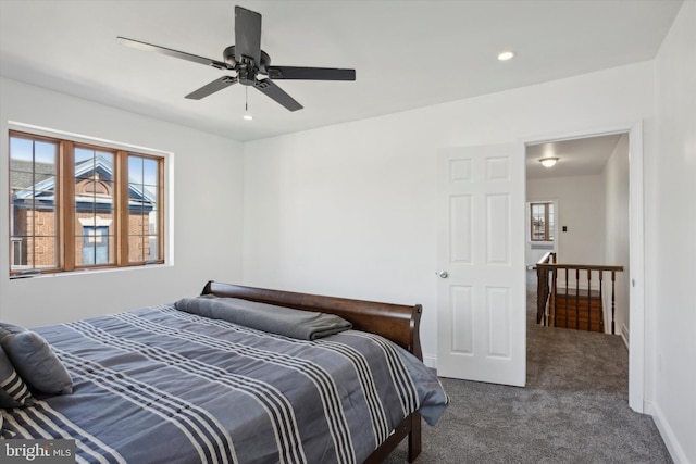 bedroom with ceiling fan, multiple windows, and dark colored carpet