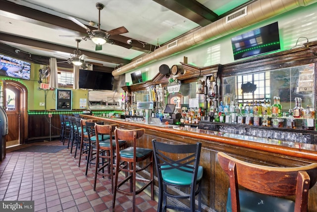 bar with ceiling fan, dark tile flooring, and beam ceiling