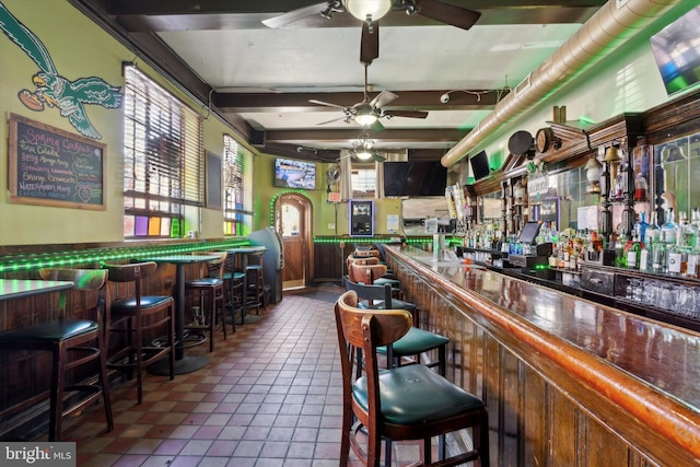 bar featuring ceiling fan, beamed ceiling, and dark tile flooring