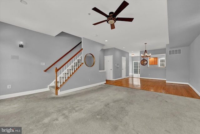 unfurnished living room featuring ceiling fan with notable chandelier and carpet