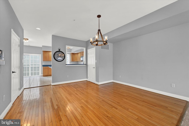 unfurnished room with light hardwood / wood-style floors and a chandelier