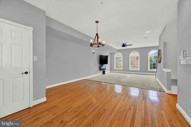 unfurnished living room with ceiling fan with notable chandelier and light wood-type flooring