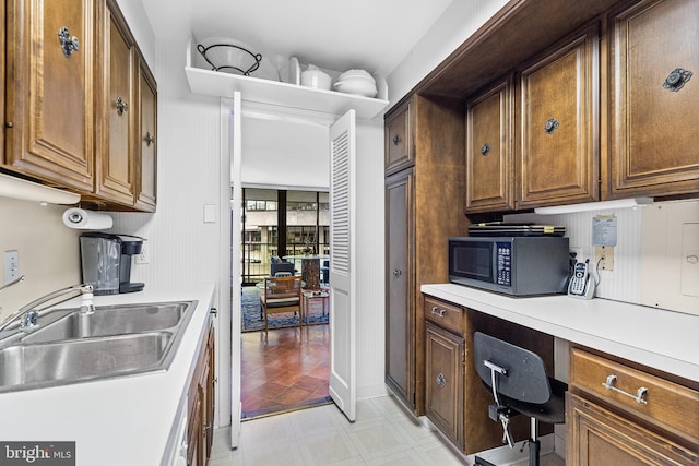 kitchen with sink, built in desk, and light tile floors