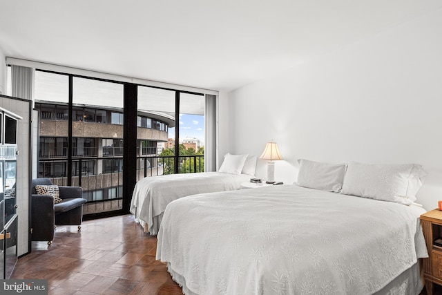 bedroom with a wall of windows, dark parquet floors, and access to outside