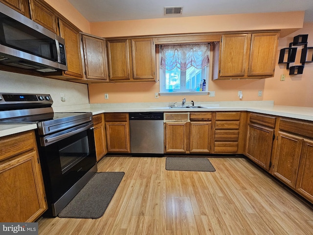 kitchen featuring appliances with stainless steel finishes, light hardwood / wood-style floors, and sink